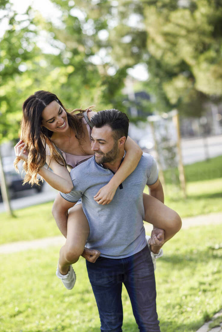 Cheerful woman holding on to boyfriends head while having piggyback ride  stock photo
