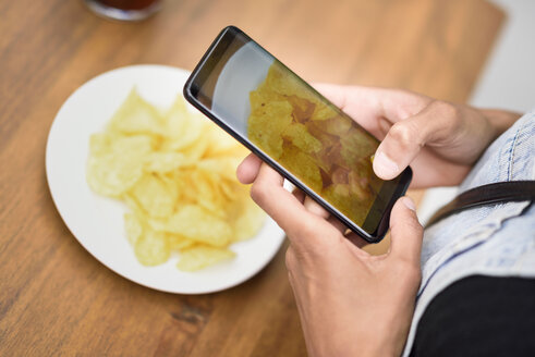 Frauenhände, die Kartoffelchips mit dem Handy fotografieren, Nahaufnahme - JSMF00357