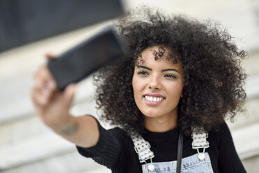 Porträt einer lächelnden jungen Frau, die ein Selfie mit ihrem Smartphone macht - JSMF00364