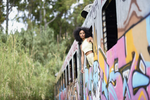 Fashionable young woman leaning out of window of an abandoned and destroyed old train stock photo