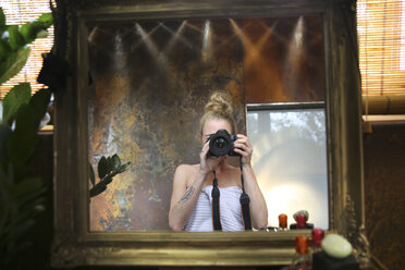 Mirror image of woman taking selfie with camera in bathroom - REAF00338