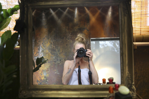 Spiegelbild einer Frau, die ein Selfie mit einer Kamera im Badezimmer macht - REAF00338