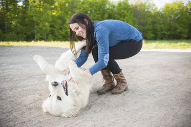 Young woman petting golden retriever on roadside - CUF34771