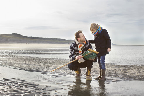 Mittelgroßer Mann und Sohn mit Fischernetz am Strand, Bloemendaal aan Zee, Niederlande - CUF34797