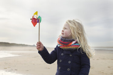 Portrait of three year old girl with paper windmill on beach, Bloemendaal aan Zee, Netherlands - CUF34821