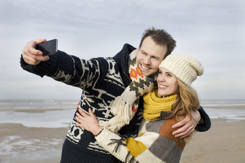 Mid adult couple taking selfie with smartphone on beach, Bloemendaal aan Zee, Niederlande - CUF34824