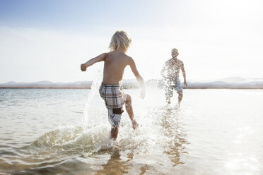 Vater und Sohn bespritzen sich gegenseitig am Strand - CUF34860