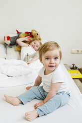 Porträt eines kleinen Mädchens auf dem Bett mit ihrer Schwester - CUF34916