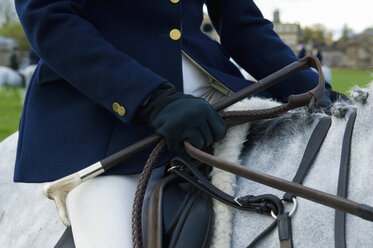 Close up cropped shot of mature woman riding grey horse - CUF34995