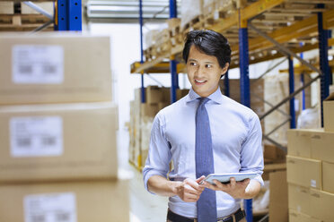 Mid adult male manager using digital tablet in distribution warehouse - CUF35023
