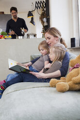 Mutter und zwei Töchter lesen ein Bilderbuch - CUF35026