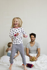 Young girl jumping on her parents bed - CUF35029