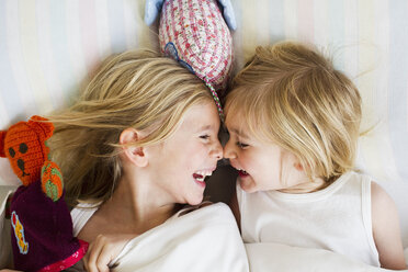 Portrait of two young sisters lying face to face in bed - CUF35044