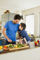 Father and young son preparing vegetables in kitchen - CUF35050