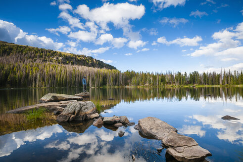 Wanderer auf einem Felsenpfad, umgeben von Wolkenreflexionen, am Quinescoe Lake, Cathedral Lakes Provincial Park, British Columbia, Kanada - CUF35098