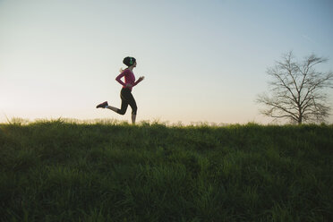Junge Läuferin mit Silhouette auf einem Hügel - CUF35138