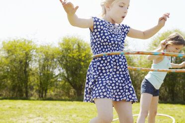 Low angle view of two girls playing with plastic hoops - CUF35153