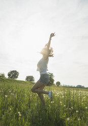 Young woman jumping in field - CUF35195