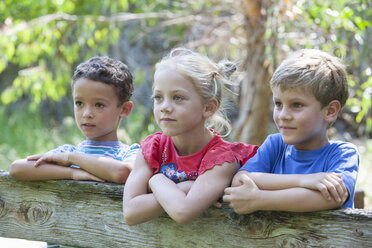 Drei Kinder lehnen am Zaun und schauen weg - CUF35251