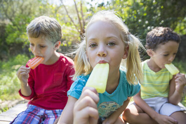 Portrait of three children in garden eating ice lollies - CUF35257