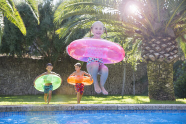 Girl jumping with inflatable ring into garden swimming pool - CUF35267