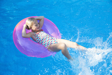 Girl lying back on inflatable ring in garden swimming pool - CUF35271