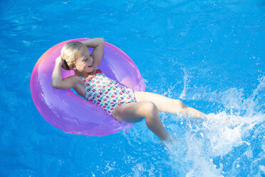 Mädchen liegt auf dem Rücken auf einem aufblasbaren Ring im Gartenschwimmbad - CUF35271