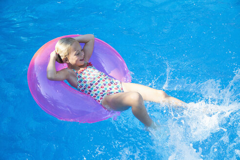 Girl lying back on inflatable ring in garden swimming pool - CUF35271
