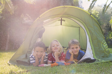 Portrait of three children lying in garden tent - CUF35279