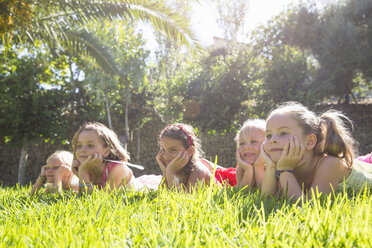 Fünf Mädchen liegen in einer Reihe im Garten mit Kinn auf Händen - CUF35326