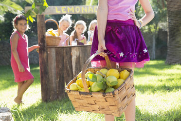 Ausschnitt eines Mädchens mit einem Korb voller Zitronen vor einem Limonadenstand - CUF35336