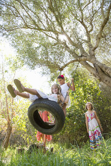Niedriger Winkel Ansicht von vier Mädchen spielen auf Baum Reifen Schaukel im Garten - CUF35346