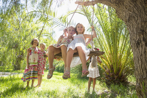 Fünf Mädchen spielen mit Baumschaukel im Garten, lizenzfreies Stockfoto