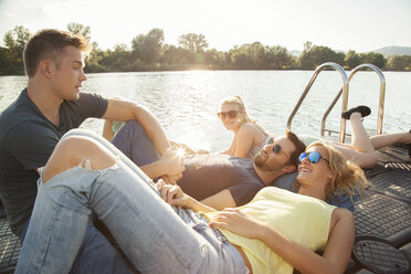 Four young adult friends chatting on riverside pier - CUF35359