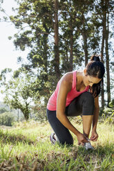 Joggerin bindet Schnürsenkel im Wald - CUF35398