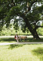 Ältere Frau sitzt auf einer Parkbank im Park - CUF35451