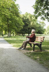 Ältere Frau sitzt auf einer Parkbank im Park - CUF35452