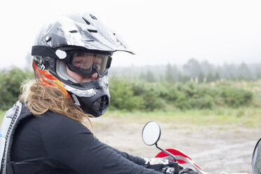 Porträt einer mittelgroßen erwachsenen Motorradfahrerin mit Sturzhelm und Schutzbrille - CUF35475