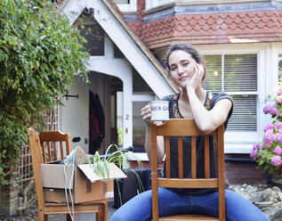 Porträt einer jungen Frau bei einer Kaffeepause vor einem neuen Haus - CUF35692