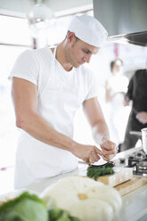 Männlicher Koch beim Mischen mit einem Kräuterschneider in einer Großküche - CUF35702