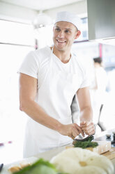 Male chef mixing chopping herbs in commercial kitchen - CUF35703