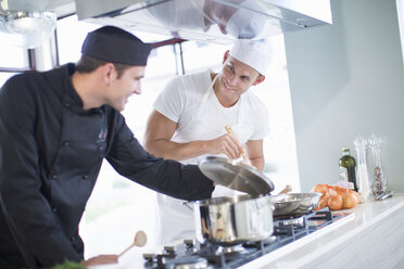 Two male chefs cooking on hob in commercial kitchen - CUF35704