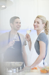Ehepaar bereitet Essen vor und trinkt ein Glas Weißwein in der Küche - CUF35708