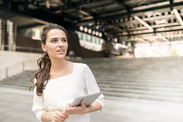 Junge Geschäftsfrau wartet vor einem Bahnhof mit einem digitalen Tablet, London, UK - CUF35715