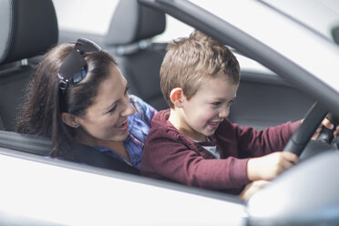 Mother and son trying out new car in car dealership - CUF35735