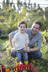 Portrait of mid adult man and son gardening in allotment - CUF35737