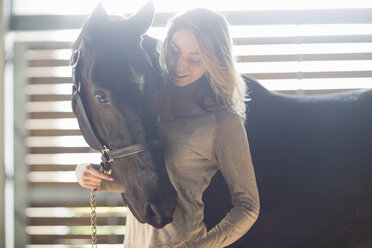 Tender portrait of young woman with black horse - CUF35747