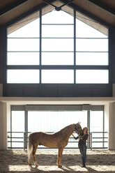 Junge Stallknechtin mit Palomino-Pferd stehend - CUF35750