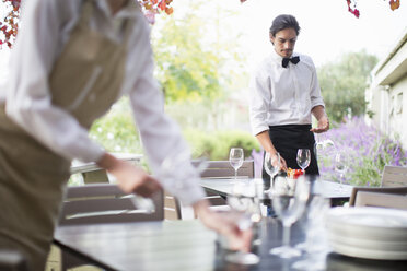 Kellnerin bereitet Weingläser auf dem Tisch im Terrassenrestaurant vor - CUF35768