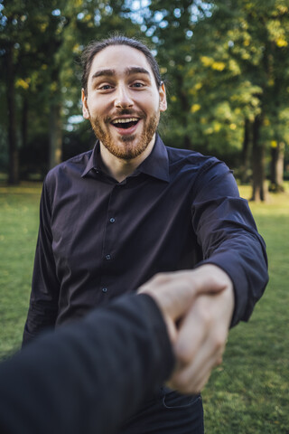 Junger Geschäftsmann, der seinen Geschäftspartner in einem Park begrüßt und über Geschäfte verhandelt, lizenzfreies Stockfoto